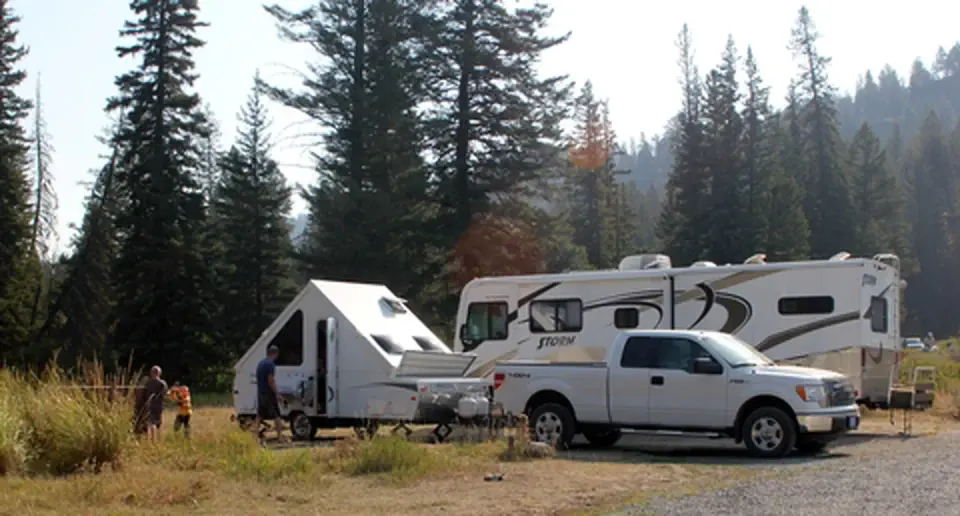 Two RVs and a white truck parked at a Slough Creek Campsite