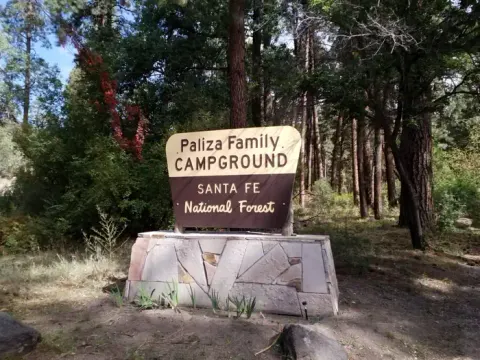 The entrance sign of Paliza Family campground surrounded by pines in the background.