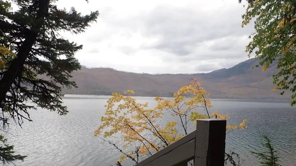 Lake McDonald with fall foliage in the foreground and mountains in the background.