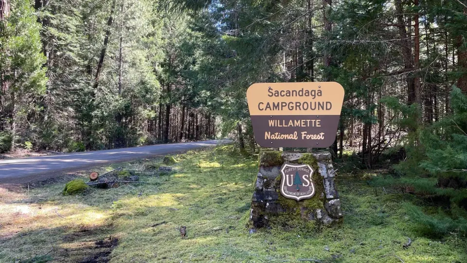 A cream and brown sign on a rock pedestal. The sign says " Sacandaga Campground".