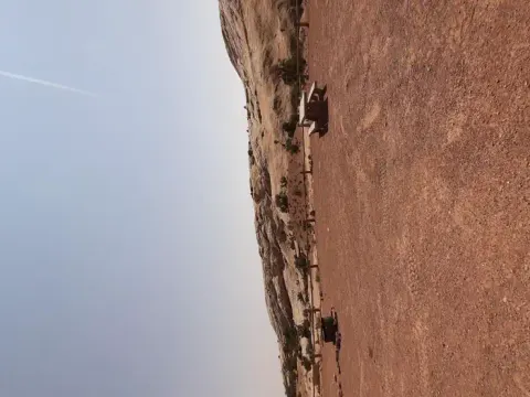 A primitive campsite on gravel ground with a fire ring and picnic table.