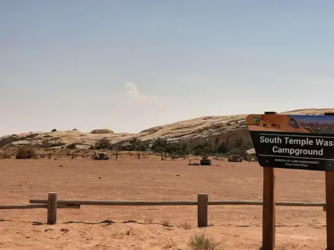 Wide angle photo of campground with sign in foreground that says "South Temple Wash"