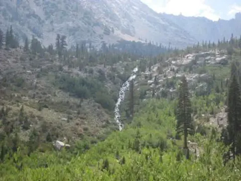 A waterfall streams down into a mountain valley