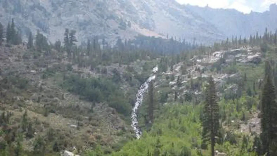 A waterfall streams down into a mountain valley
