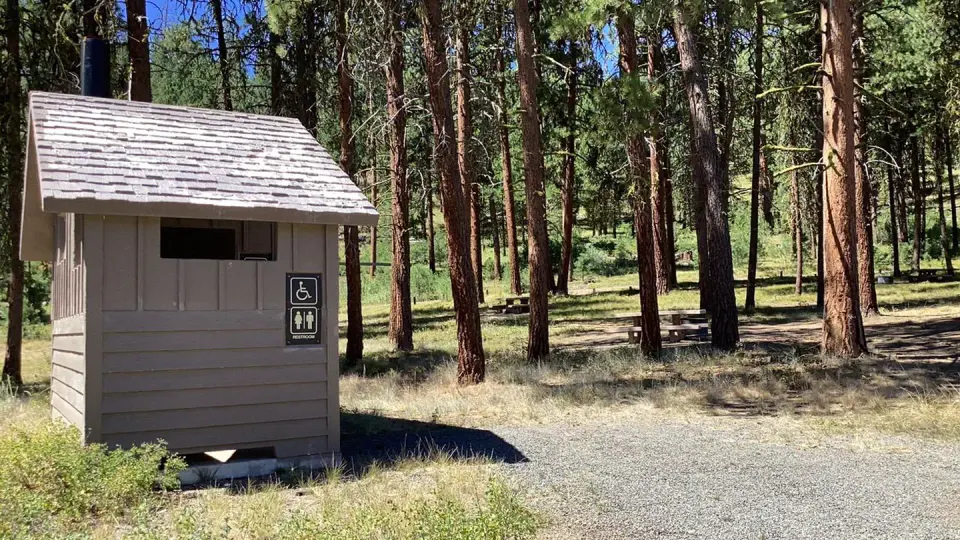 vault toilet and campsite in background